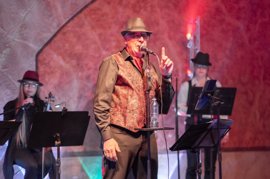 Solisti Jorma Valli laulamassa Sointu Ensemblen Leonard Cohen -konsertissa, taustalla viulisti ja toinen taustalaulajista. Leonard Cohen suomeksi